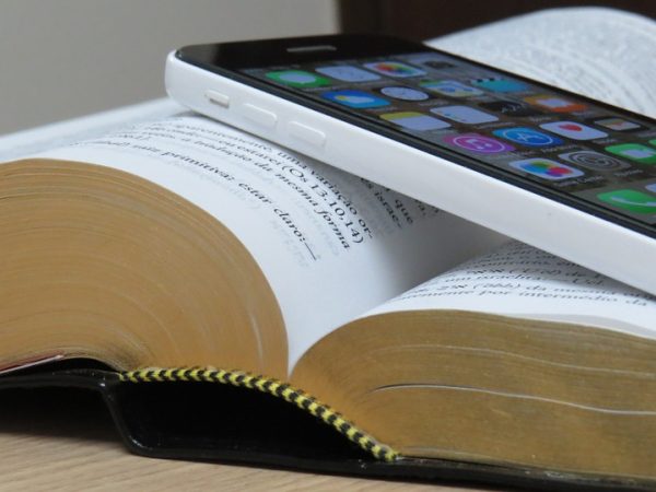 open Bible with an iPhone laying on top of the open pages
