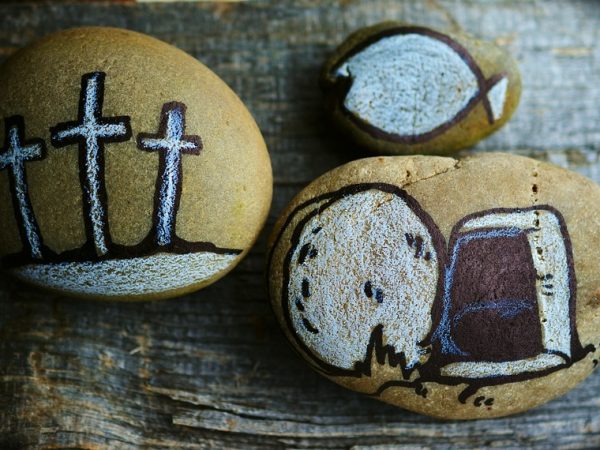 three small decorative stones, one with three crosses, one with a fish and the last with a cut loaf of bread